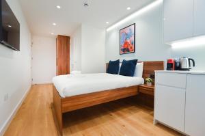 a small bedroom with a bed and a kitchen at West Hampstead Serviced Apartments in London