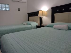2 camas en una habitación de hotel con sábanas verdes en Mi Depa Cascada, en Ciudad Valles
