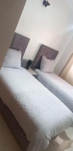 - 2 lits installés l'un à côté de l'autre dans une chambre dans l'établissement Nahililan Appartement, à Marrakech