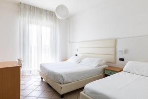 a hotel room with two beds and a window at Hotel Palos in Rimini