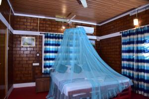 - une chambre avec un lit doté d'une moustiquaire bleue dans l'établissement Doctors Ayurveda Heritage, à Varkala