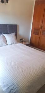 - une chambre avec un grand lit blanc et une armoire en bois dans l'établissement Nahililan Appartement, à Marrakech
