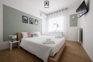a white bedroom with a bed and a tv at Junior Suite in Naples
