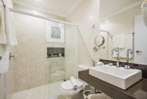 a bathroom with a sink and a toilet and a shower at Hotel Estoril in Campos do Jordão