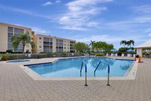 a large swimming pool in a resort with palm trees at Island-style condo with pool, spa and steps to beach in Marco Island
