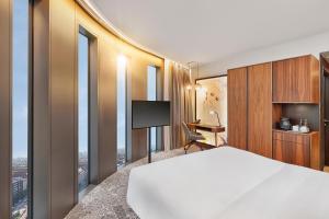 um quarto de hotel com uma cama, uma secretária e janelas em HYPERION Hotel München em Munique