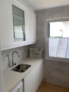 a white kitchen with a sink and a window at Apartamento con preciosa vista al mar y AA in Son Parc