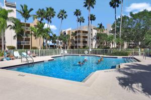 a pool with people in it with palm trees and buildings at Tranquil waterfront condo with pool and steps to beach in Marco Island