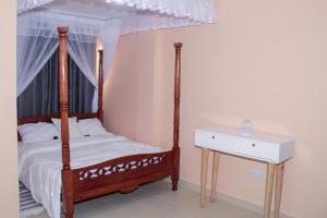a bedroom with a canopy bed and a white table at Royal Palms Executive 2& 1 bedrooms BNB Wote town in Wote