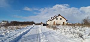 una casa en un camino cubierto de nieve en un campo en Zimna Apartments, en Kwidzyn