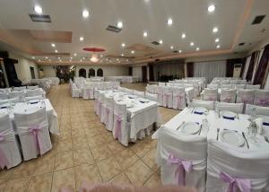 - une salle de banquet avec des tables et des chaises blanches avec des archets violets dans l'établissement Hotel Nautilos, à Sozopoli