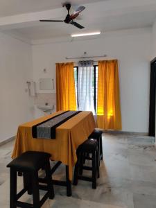 een kamer met een tafel met stoelen en gele gordijnen bij Andoor Homes, Apt 2D in Trivandrum