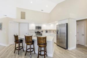 Una cocina con gabinetes blancos y un refrigerador de acero inoxidable. en Waterfront home with spectacular view, pool and spa, en Marco Island