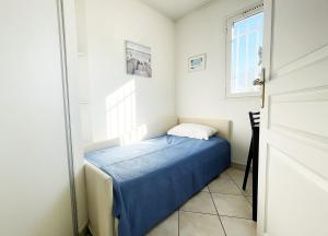 Un pequeño dormitorio con una cama azul y una ventana en Appartement 215 supérieur - LES SUITES DE ROBINSON - Résidence avec piscine en bord de Siagne, à Mandelieu-La-Napoule, en Mandelieu-la-Napoule