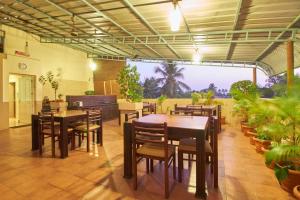 un restaurante con mesas de madera, sillas y plantas en Fort Abode, en Kochi