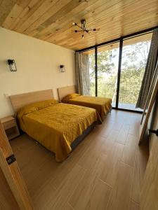 2 letti in una camera da letto con soffitti e finestre in legno di Cabaña La Finca Mazamitla a Mazamitla