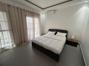 a bedroom with a bed with white sheets and windows at Jumeirah on the hills, Mamelles in Dakar