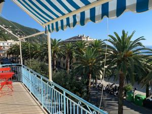 a balcony with palm trees and a blue and white umbrella at Il cuore di Moneglia - MONEGLIA APARTMENTS in Moneglia