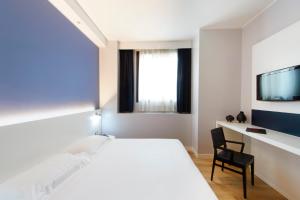 a bedroom with a bed and a desk and a tv at Neo Hotel in Bresso