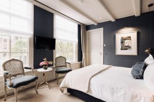 a bedroom with a bed and chairs and a tv at Hotel 717 in Amsterdam