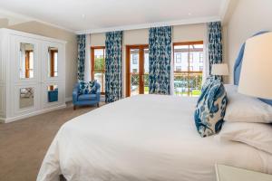 a bedroom with a large bed with blue curtains at The Plettenberg Hotel in Plettenberg Bay