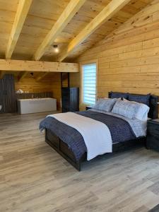 a bedroom with a large bed in a wooden room at Chalets domaine Otis in Saint-Félix-d'Otis