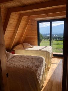 two beds in a room with a large window at Hacienda El Rejo in Machachi