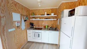 a kitchen with a white refrigerator and wooden walls at Gotuhus - Sea View Apartment in Hellissandur