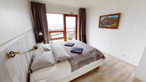 a bedroom with a bed with a window and a lamp at Gotuhus - Sea View Apartment in Hellissandur