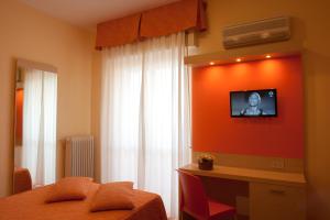 ein Schlafzimmer mit einem Bett und einem TV an der Wand in der Unterkunft Hotel Regent in Pescara