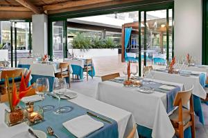 a restaurant with white tables and chairs and windows at Hotel Gran Canaria Princess - Adults Only in Playa del Ingles