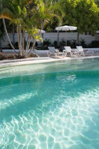a swimming pool with two chairs and an umbrella at Hotel Gran Canaria Princess - Adults Only in Playa del Ingles