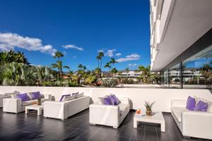 an outdoor patio with white couches and purple pillows at Hotel Gran Canaria Princess - Adults Only in Playa del Ingles