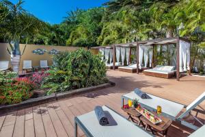 a resort with beds and a deck with trees at Hotel Gran Canaria Princess - Adults Only in Playa del Ingles