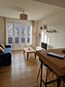 ein Wohnzimmer mit einem blauen Sofa und einem Tisch in der Unterkunft Le Portel Plage les 4 saisons 2 in Le Portel