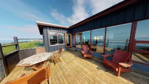 a deck with a table and chairs on a house at Kleifar: Ocean View Apartment in Hellissandur