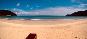 a wooden bench on a beach with the ocean at Tiongman Scubadive & Lodge in Tioman Island