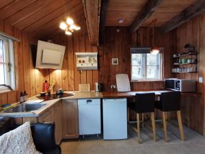 a kitchen with wooden walls and a counter with chairs at Birkevang The Silo - Rural refuge in Faxe