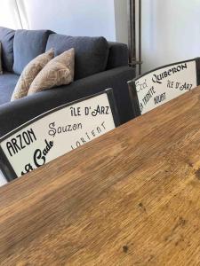 a wooden table in front of a couch with pillows at TY DOLMEN DU Plages à pied 2 vélos WIFI in Carnac