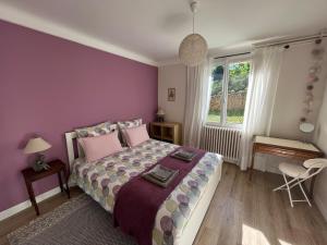 1 dormitorio con cama y pared púrpura en SARLAT Centre ville - Appartement avec jardin et piscine, en Sarlat-la-Canéda