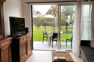 a living room with a television and a table with chairs at TY DOLMEN DU - 2 vacanciers - Jardin clos - Petit chien bienvenu - 2 vélos - Plages et Commerces à pied in Carnac