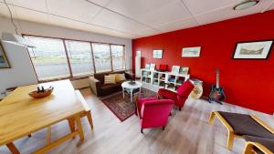 a living room with red walls and a table and chairs at Brenna: Cliffside Apartment in Hellissandur