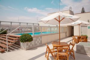 un patio con piscina, mesas y sombrilla en Dorado Hotel Boutique - Tacna, en Tacna