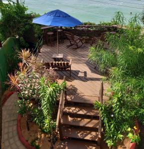 eine Holzterrasse mit einem blauen Sonnenschirm und Stühlen in der Unterkunft Casa Serena in Pipa