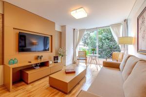 ein Wohnzimmer mit Sofa und Fernseher in der Unterkunft Rosa Edifício Giovani Pizetta in Gramado