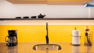 a kitchen counter with a sink and yellow tiles at Topá House in Medellín