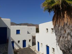 a row of white buildings with blue doors and a palm tree at Silver Rocks Hotel in Chrissi Akti