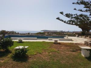 a park with benches in the grass and a building at Silver Rocks Hotel in Chrissi Akti