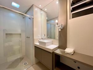 y baño blanco con lavabo y ducha. en Apto Altos de Gramado 3 dorm by Achei Gramado, en Gramado