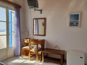 a room with a chair and a table and a mirror at Silver Rocks Hotel in Chrissi Akti